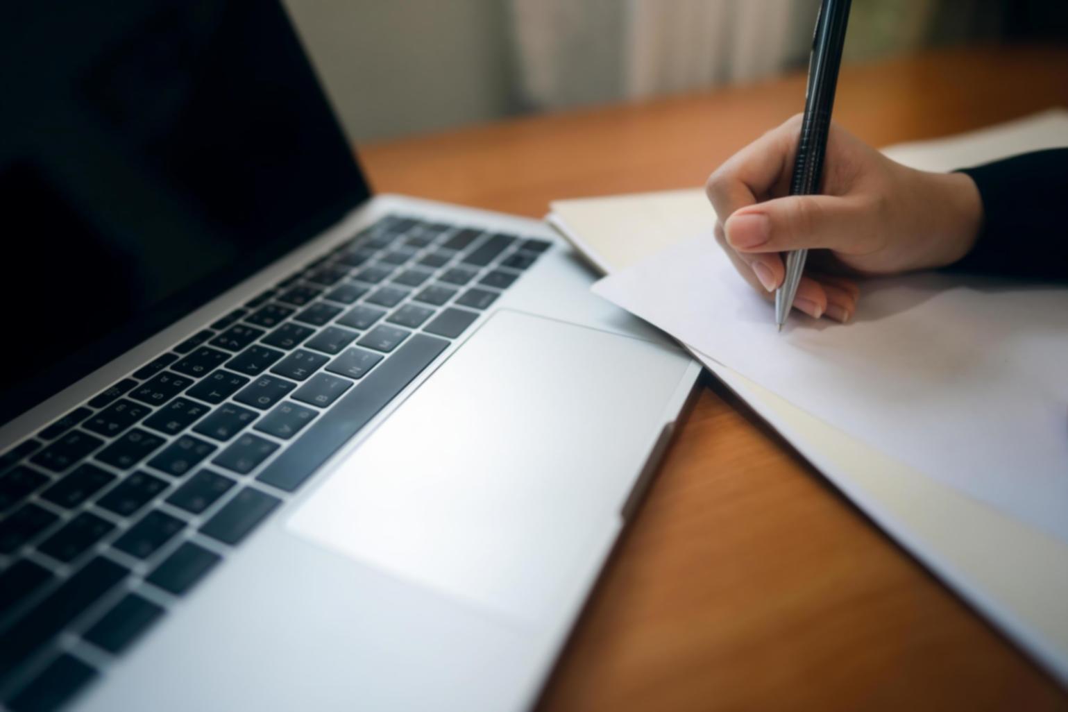 Person reviewing financial statements and receipts with laptop open